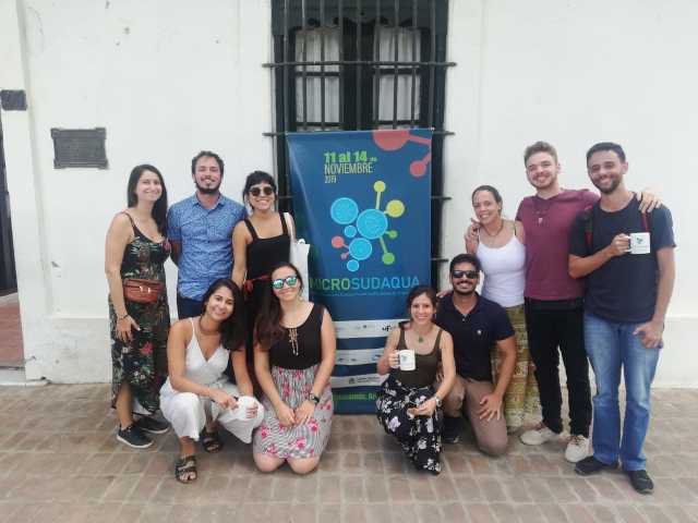 10 pessoas em frente ao pôster do MicroSudAqua, 2019, em Chascomús - Argentina.